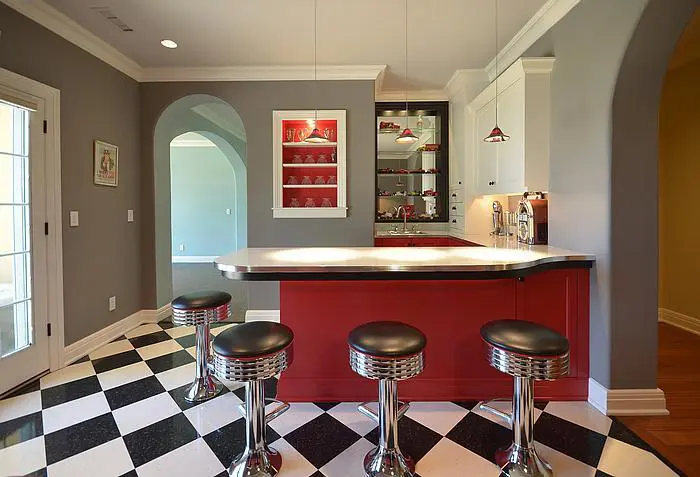 A kitchen with black and white checkered floor, red counter top.