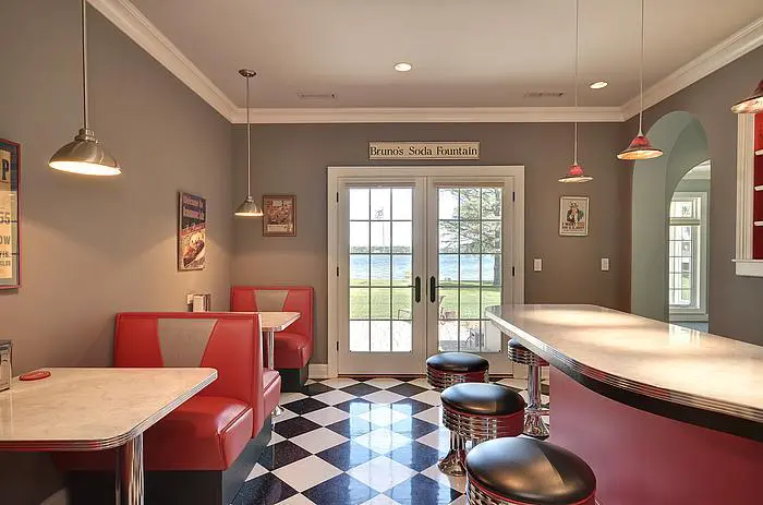 A kitchen with black and white checkered floor, red booths and two tables.