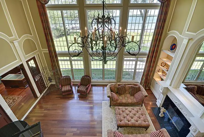 A living room with two large windows and a chandelier.