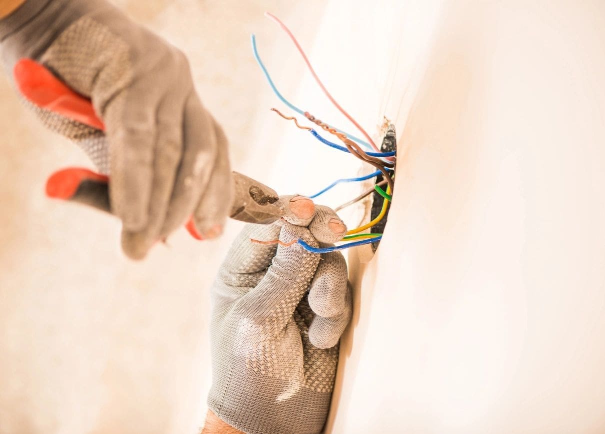 Electrician cutting multicolored wires with pliers